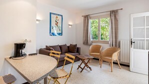 A living room with a round table, two chairs, a sofa, a coffee machine, and a window with curtains. - Flat in a Beautiful Building With Pool (Meze)