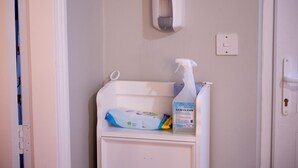 Un bagno con un erogatore di disinfettante per le mani, un fasciatoio e una bottiglia per neonati.