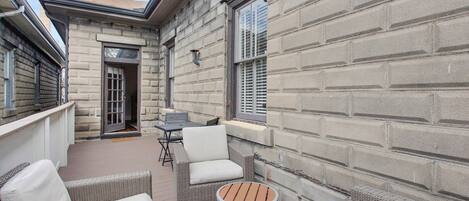 A patio with wicker furniture, a small round table, and a window with shutters.