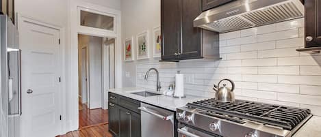 A modern kitchen with dark wood cabinets, stainless steel appliances, and a tiled backsplash.