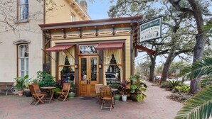 Un espacio al aire libre acogedor con sillas y mesas de madera, un letrero de 'Mate Factor Coffee & Bakery' y un gran árbol al fondo.
