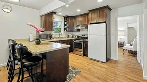 A modern kitchen with wooden cabinets, a central island, and stainless steel appliances.