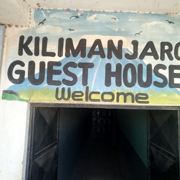 A sign for the Kilimanjaro Guest House with the word "Welcome" below it.