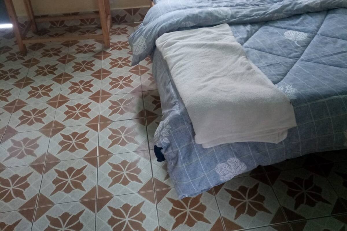 A bedroom with a bed, a bedside table, and a patterned floor.