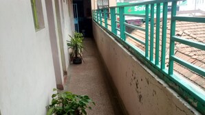 A narrow corridor with potted plants, a green railing, and a visible Safaricom sign in the background. - Kilimanjaro Guest House (Nakuru)