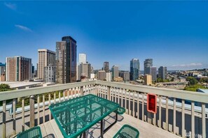 Enjoy breathtaking views of the city skyline from this balcony, featuring a table and two chairs.