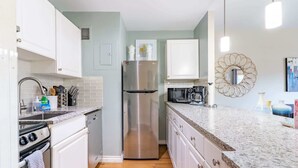 A modern kitchen with white cabinets, a stainless steel refrigerator, a microwave, and a coffee maker. - Vibrant 1B Downtown Condo near Convention Center (Seattle)