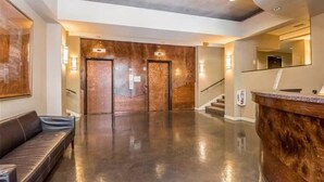 A modern lobby with a polished floor, a reception desk, and a staircase leading to another level. - Vibrant 1B Downtown Condo near Convention Center (Seattle)