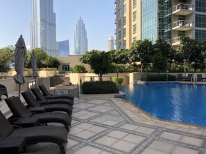 A rooftop pool area with lounge chairs and a view of tall buildings in the background. - Elite Royal Apartment - Burj Khalifa & Fountain view - Crystal (Dubai)
