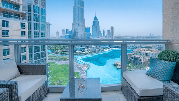 Un balcone con vista sullo skyline urbano, che include una torre imponente e un corpo d'acqua con un ponte.