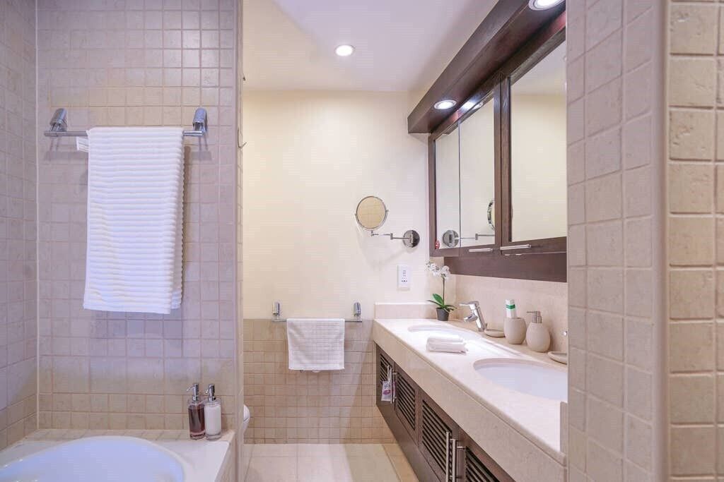 A modern bathroom with a bathtub, a large mirror, and a vanity with a sink and toiletries.