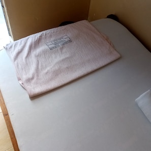 A neatly folded white towel on a bed with a visible hotel name tag. - Marico Guest House (Nakuru)