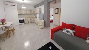 A compact living space with a dining area, kitchenette, and a sofa with a pillow. - Greek Pride Evlogia (Kassandra)