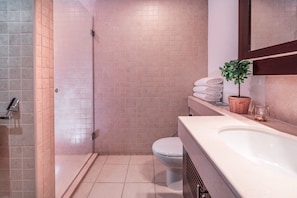 Een badkamer met douche, toilet en wastafel.