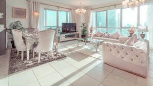 Un salón amplio con una televisión grande, un sofá y un comedor con sillas.