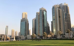 Urban high-rise buildings surround a lush, landscaped public space.