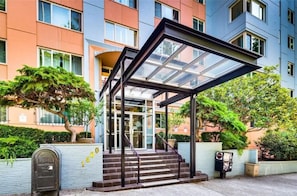Stunning hotel entrance with a glass-enclosed outdoor area and a set of stairs leading up to the door.