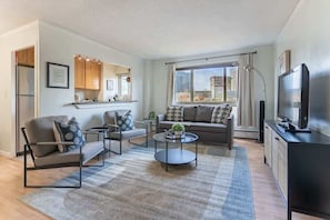 Relax in this stylish living room with a sofa set, coffee table, and flat-screen TV, offering a view of the city.