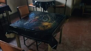 A dining area with a round table covered in a black tablecloth, surrounded by four chairs.