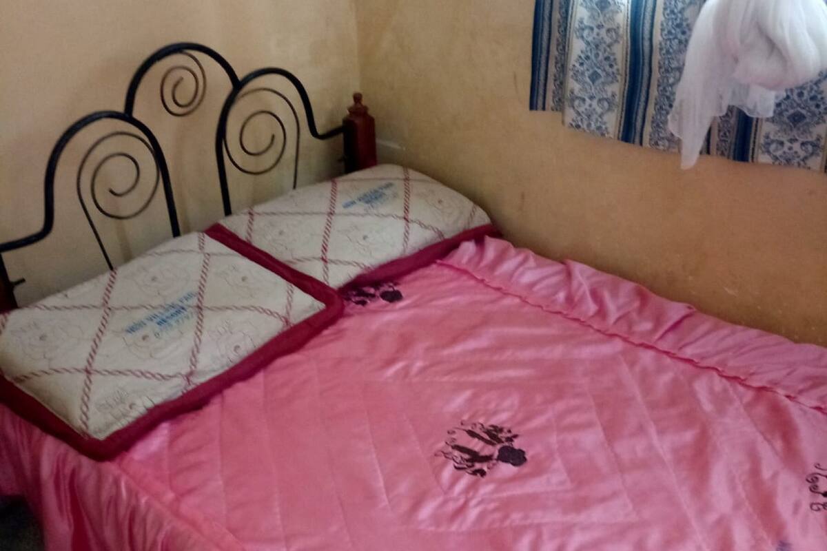 A bed with a pink bedspread and a headboard.