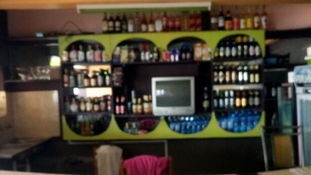 A bar area with a counter and shelves stocked with bottles.