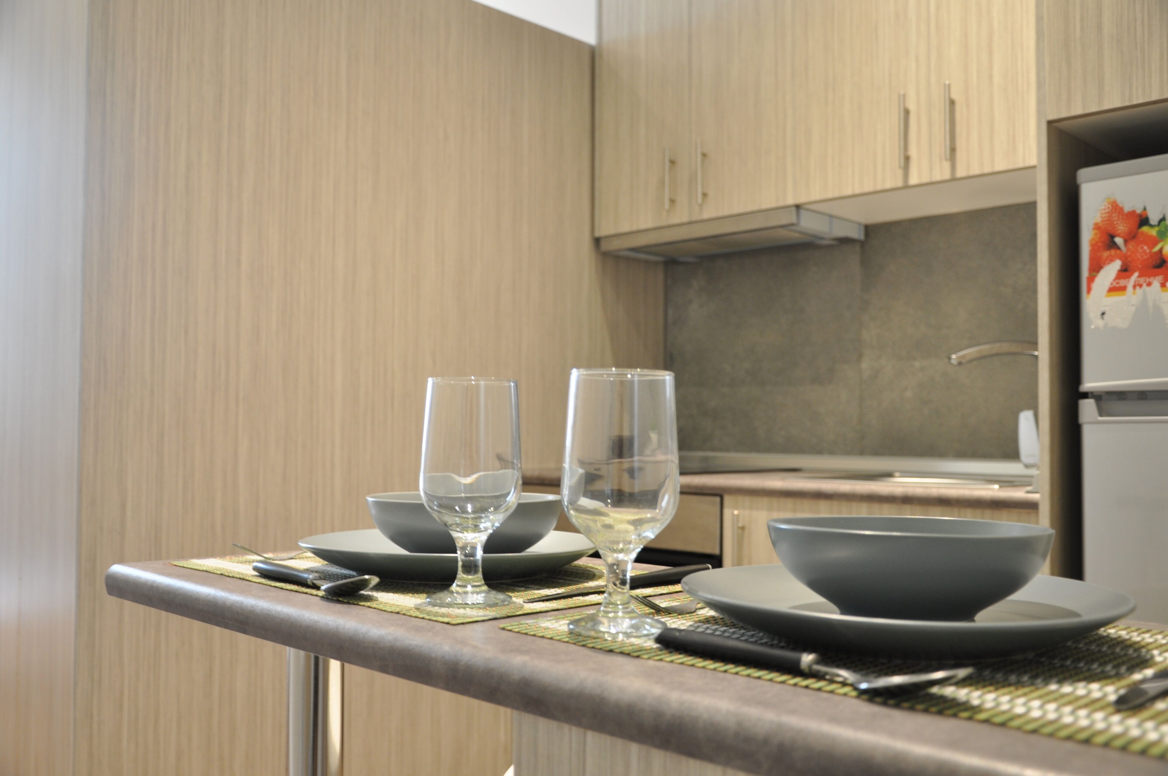 A kitchen with a dining area, including a table set with two wine glasses, bowls, and plates.