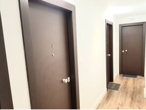 A hallway with two dark wooden doors, each with a small window and a doorbell. - Penthouse Apartments, The Luxury Suites (Thessaloniki)
