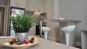 A modern kitchen with a potted plant on a tray, a white pedestal sink, and a clock on the wall.