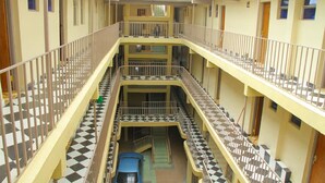 Un atrium à plusieurs niveaux, doté d’un escalier central, de balcons et d’une voiture bleue garée au niveau inférieur.