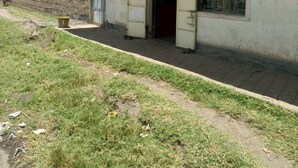A building labeled "Njiwa Guest House" with a simple entrance and a small outdoor area with a trash bin. - Njiwa Guest House (Nakuru)