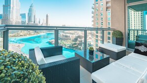 Ein Balkon mit Korbmöbeln, einem Glastisch und Blick auf Stadt und Wasser.