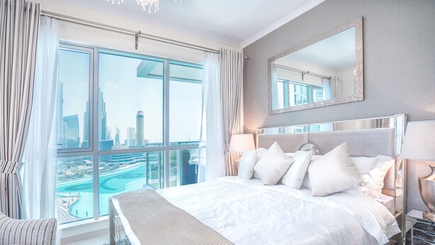 Ein modernes Hotelzimmer mit einem großen Bett, Blick auf die Stadt und einem großen Spiegel.