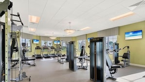 Une salle de sport équipée de machines de cardio, de matériel de musculation et de miroirs aux murs.