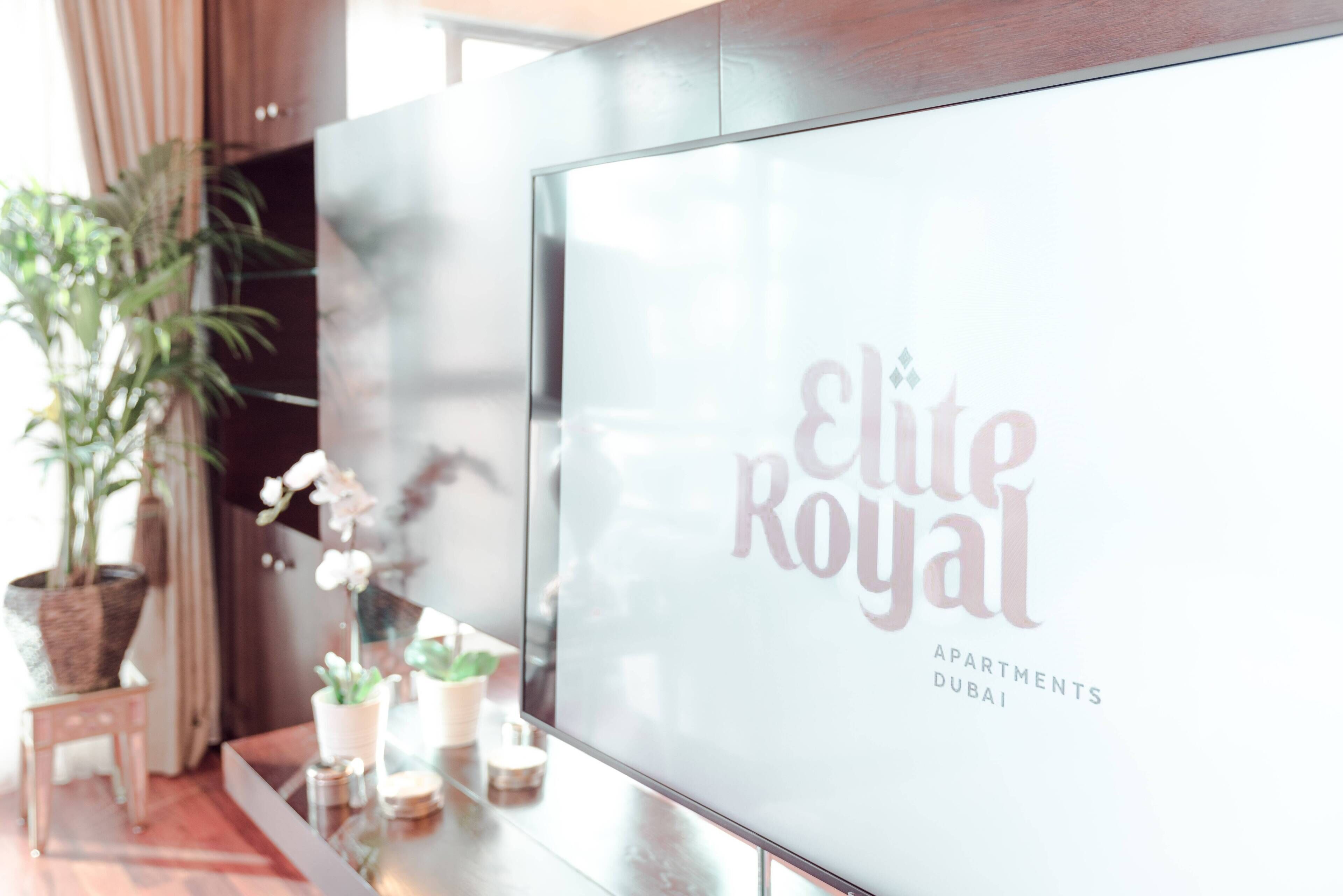 A modern interior with a large glass display featuring the text "elite Royal Apartments Dubai".
