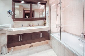 Une salle de bain moderne avec un grand miroir, deux vasques, des meubles en bois foncé et une douche à parois de verre.