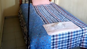 Uma cama de solteiro com colcha xadrez, um travesseiro rosa e um dossel.