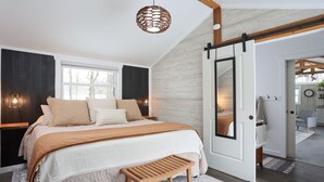 A bedroom with a bed, wooden bench, and a sliding door leading to another room.