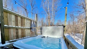 An outdoor hot tub with a wooden deck and a wooden fence.