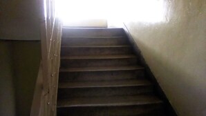 A wooden staircase with a handrail leading to a landing. - Pekers Lodge (Nakuru)