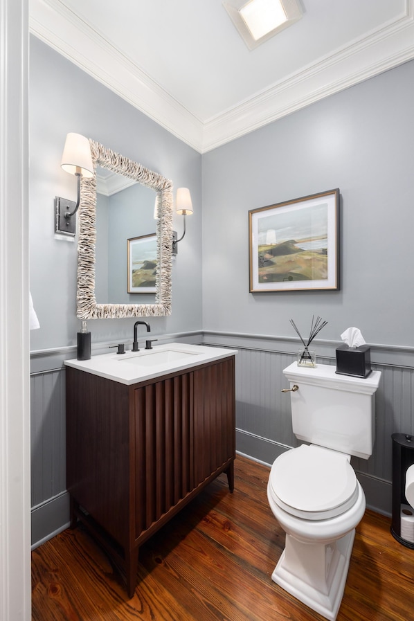 A bathroom with a wooden vanity, white sink, and a toilet.