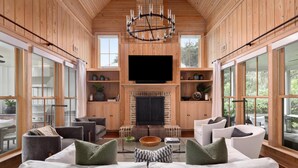 A spacious living room with a large TV, wooden walls, and a fireplace.