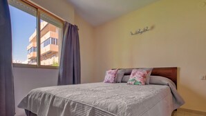 A bedroom with a bed, curtains, a window, and a wall-mounted shelf. - Lovely apartment for 4 people with WIFI, A/C, TV and pets allowed (Calpe)