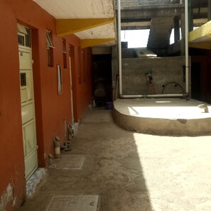 A corridor with a concrete floor, a door labeled "03" on the left, and a window on the right.