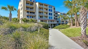 A multi-story hotel with balconies, surrounded by palm trees and a pathway. - Shipwatch #1365 - Heated Pool! (Fernandina Beach)