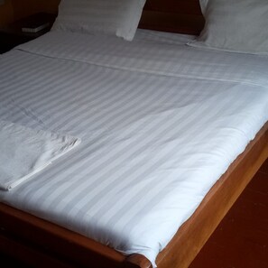 A bed with a striped bedspread and pillows. - Rigena Lions Hotel (Nakuru)