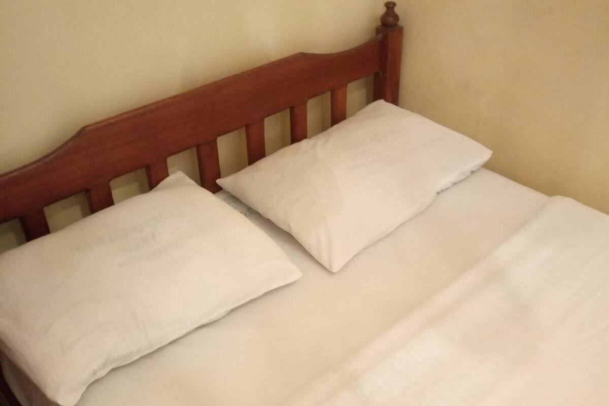 A bed with a wooden headboard and two pillows.