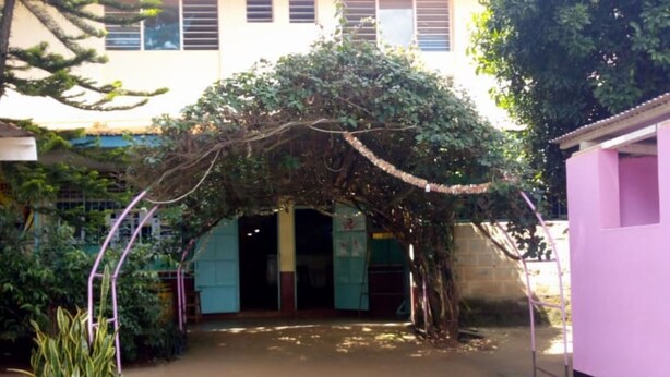 A courtyard with a covered walkway, surrounded by buildings and greenery. - Sagana Country Hotel (Nyeri)