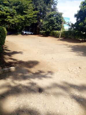 A dirt road with a parked car and dense trees on both sides. - Sagana Country Hotel (Nyeri)