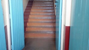 A narrow hallway with a wooden staircase leading to a landing. - Sagana Country Hotel (Nyeri)