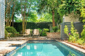 A swimming pool with tiled edges, surrounded by a garden with trees and plants. - Bright & Secluded Apartment with Pool Access (Charleston)